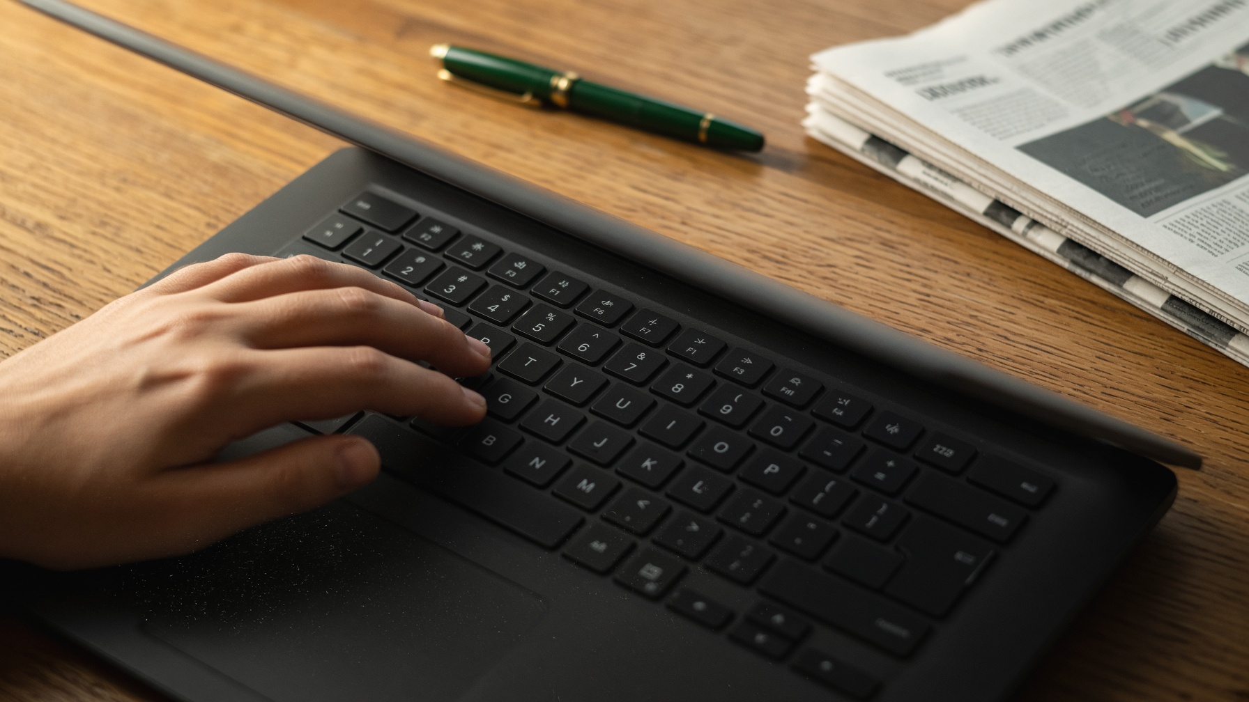 Close-up of a laptop keyboard on an oak desk, late-afternoon Irish interior light.